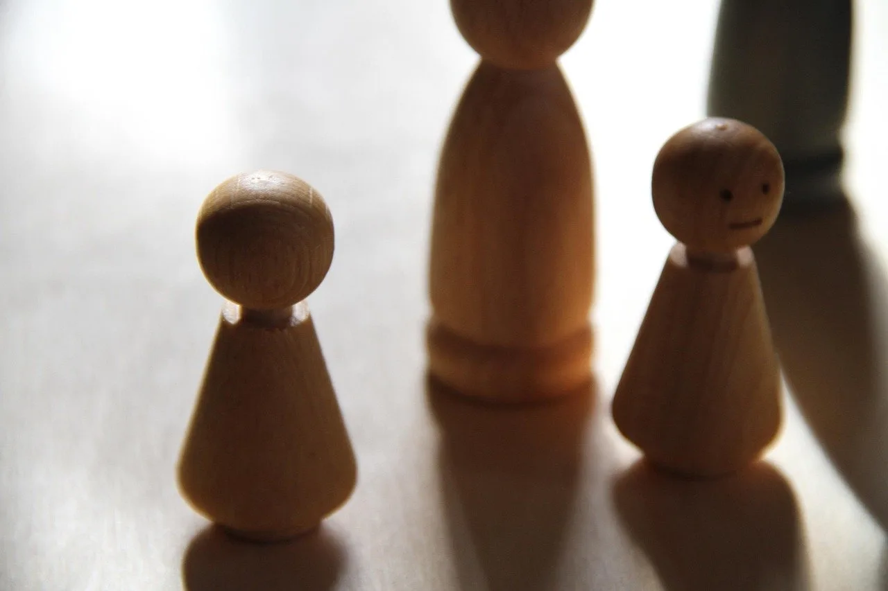 Three wooden peg-doll figures representing family members standing on a table.