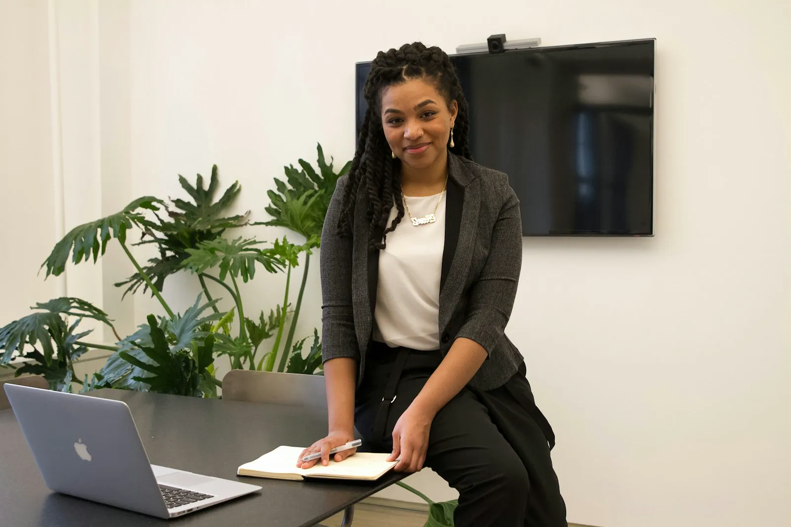 A professional woman works thoughtfully at her laptop at an office desk.