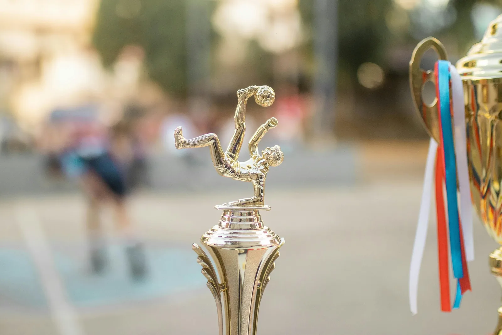 A close-up of a trophy shaped like a soccer player mid-kick, with another trophy beside it.