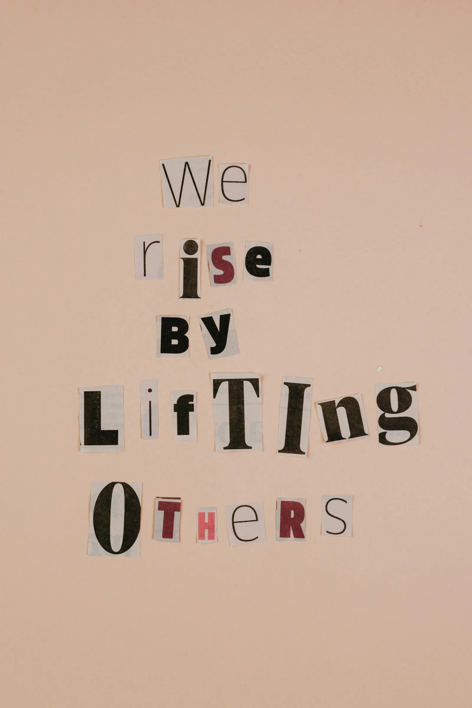 A handmade sign made of cut-out letters spelling "We rise by lifting others."