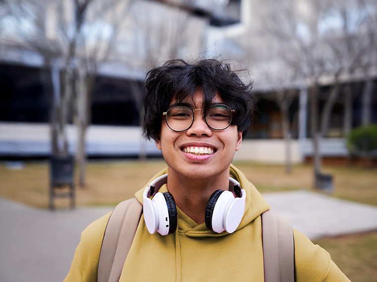 A teenager standing thoughtfully outdoors in warm light.